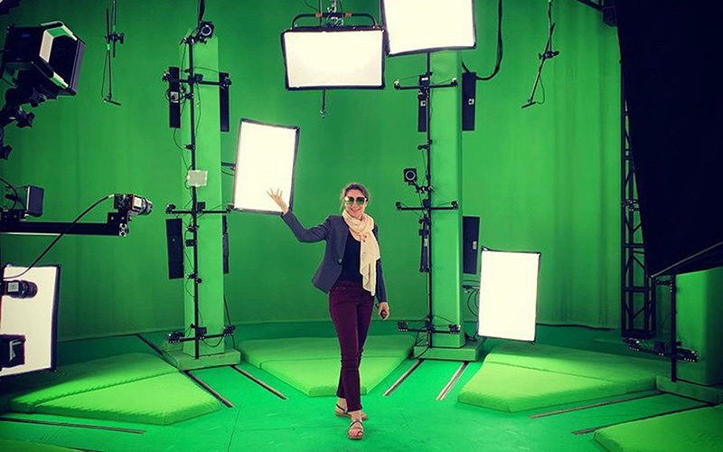 Zuzana standing in the middle of a green room surrounded by scanning apparatus used for generating VR 3D spatial video scans